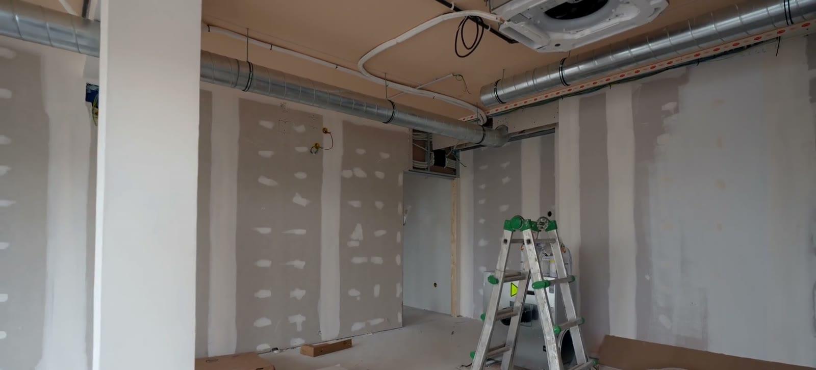 Exposed spiral ductwork and conduit run through a building under fit-out